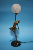 An Art Deco style figural table lamp, the lady holding aloft the shade.