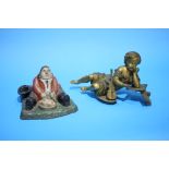 A cast iron and painted inkwell of a seated man eating dinner and a gilt metal figure.