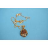 An 18ct gold chain with pierced foliate pendant, set with seven small ruby coloured stones