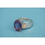 An 18ct gold ring set with large central purple coloured stone and flanked by two rows of three