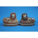 A near pair of Staffordshire pot lions with glass