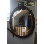 An oval mirror decorated with carved bows and foli