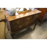 An oak lowboy with three short drawers over one long drawer