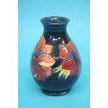 A modern Moorcroft vase on a dark blue ground, decorated with a band of flowers, impressed marks.