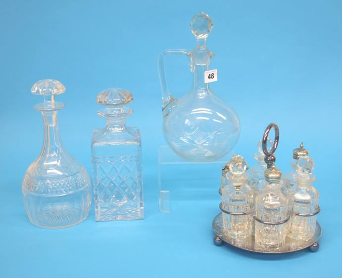 A silver plated six bottle cruet and three clear glass decanters.