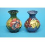 Two Moorcroft vases on a blue ground and green ground, decorated with flowers.