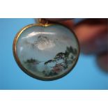 A double reverse painted glass pendant, decorated with landscapes in silver mounts 3cm lenth