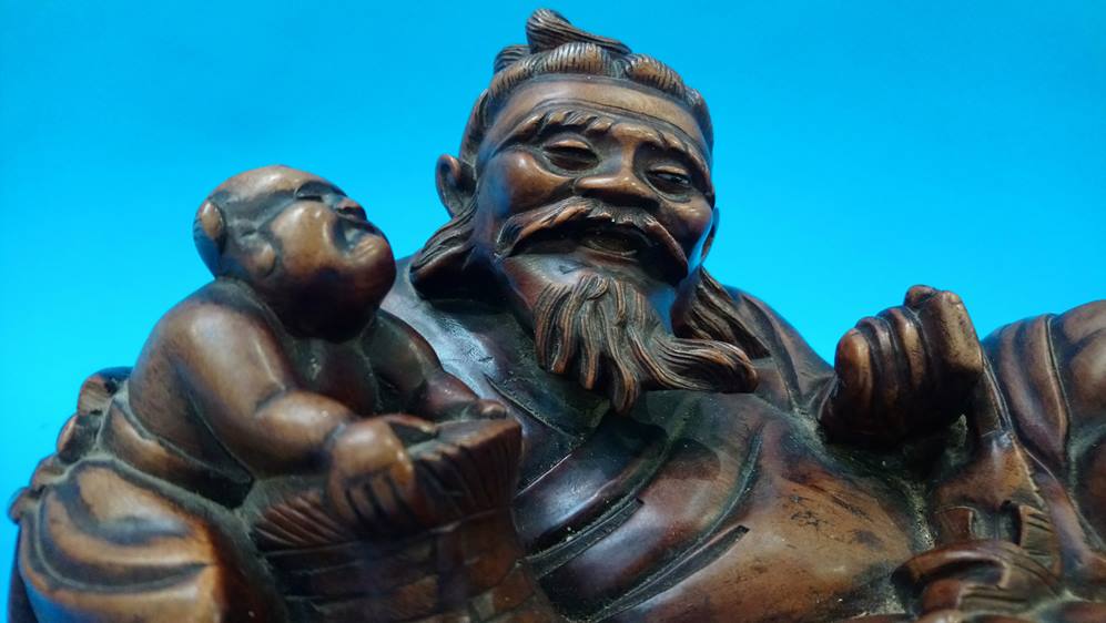 An Oriental hardwood figure of a recumbent fisherman on stand - Image 2 of 2