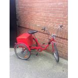 Three wheeled red tricycle with back box