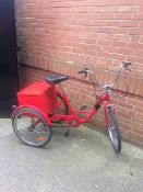 Three wheeled red tricycle with back box