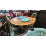 A pale oak Ercol style gateleg table and four chairs.