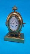 A small brass mantel clock with oval enamelled dial, stamped S. and F. 23cm high