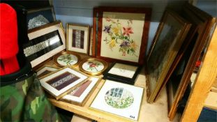 A shelf of embroidered and needlework pictures.