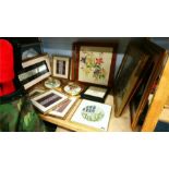 A shelf of embroidered and needlework pictures.