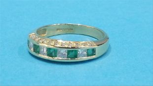 An 18ct gold diamond and emerald ring, with a row of diamonds to each side.