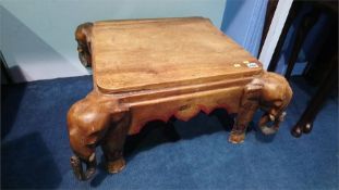 A hardwood occasional table with carved elephants