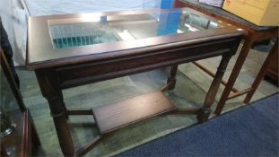 An oak glass top display table with locking drawer