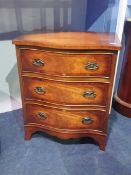 A small serpentine fronted reproduction mahogany chest of drawers, with three drawers