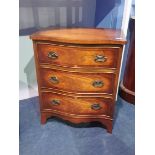 A small serpentine fronted reproduction mahogany chest of drawers, with three drawers