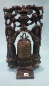 An Oriental hanging bell, set in a carved wood framework and standing on a circular table