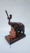 An inkstand in the form of an ebonised elephant standing on a book, with stoneware inkwell