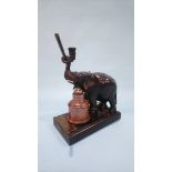 An inkstand in the form of an ebonised elephant standing on a book, with stoneware inkwell