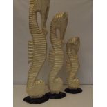 Three painted graduating seahorse figures, largest