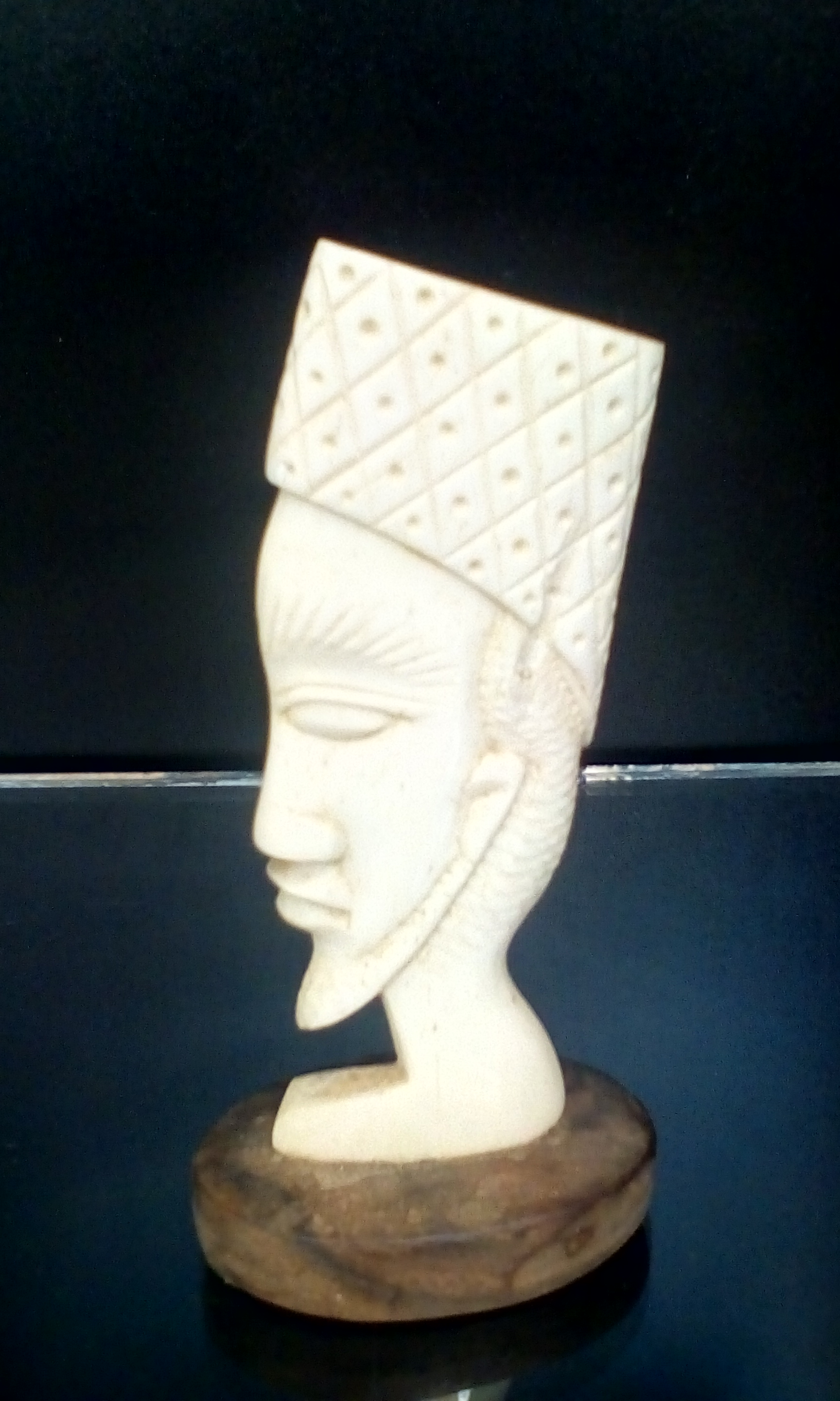 Carved bone head on a wooden plinth base