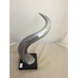 A polished aluminium sculpture of a horn