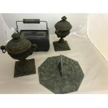 A pair of metal urns: sundial and heater box