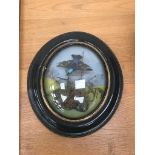 An oval framed and glazed taxidermy of a hummingbird above a floral diorama