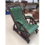 A green leather reclining chair with ship's wheel sides and plaque of a Phoenix, New Orleans,