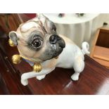 A ceramic painted pug with collar and bell