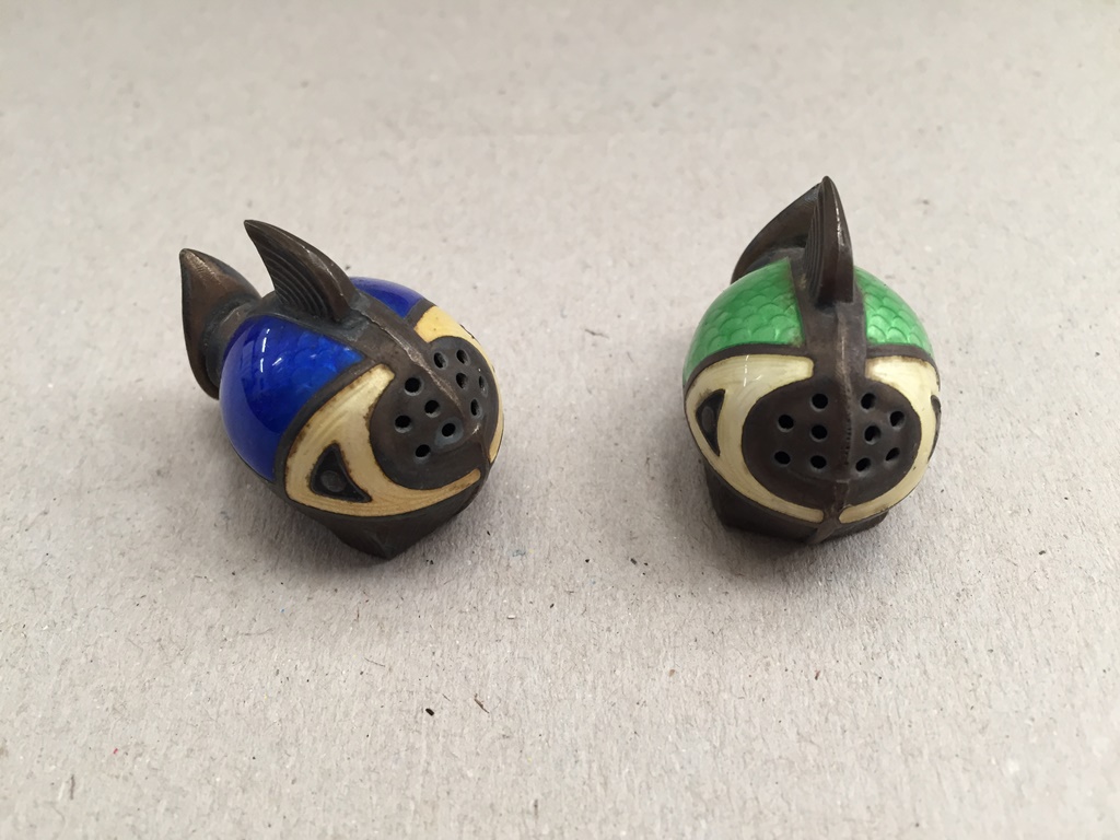 A pair of white metal and enamel pepper pots
