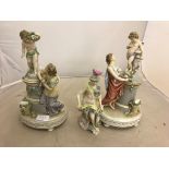 A pair of 19/20th century figurines of ladies with Cupid standing on a column;