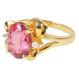 An 18ct Pink Tourmaline and Diamond Dress Ring: Hallmarked 18k set with an oval cut pink tourmaline