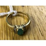 An 18ct oval cut emerald ring with channel set diamond to the shoulders