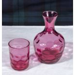 A cranberry glass carafe and glass