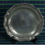 A pewter plate with scalloped edge