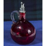 A cranberry glass decanter with white metal stopper