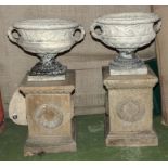 A pair of stone urns on stands