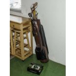 A set of golf clubs, bag and an auto putt trainer