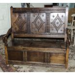 A late Victorian carved oak settle with lift up seat.