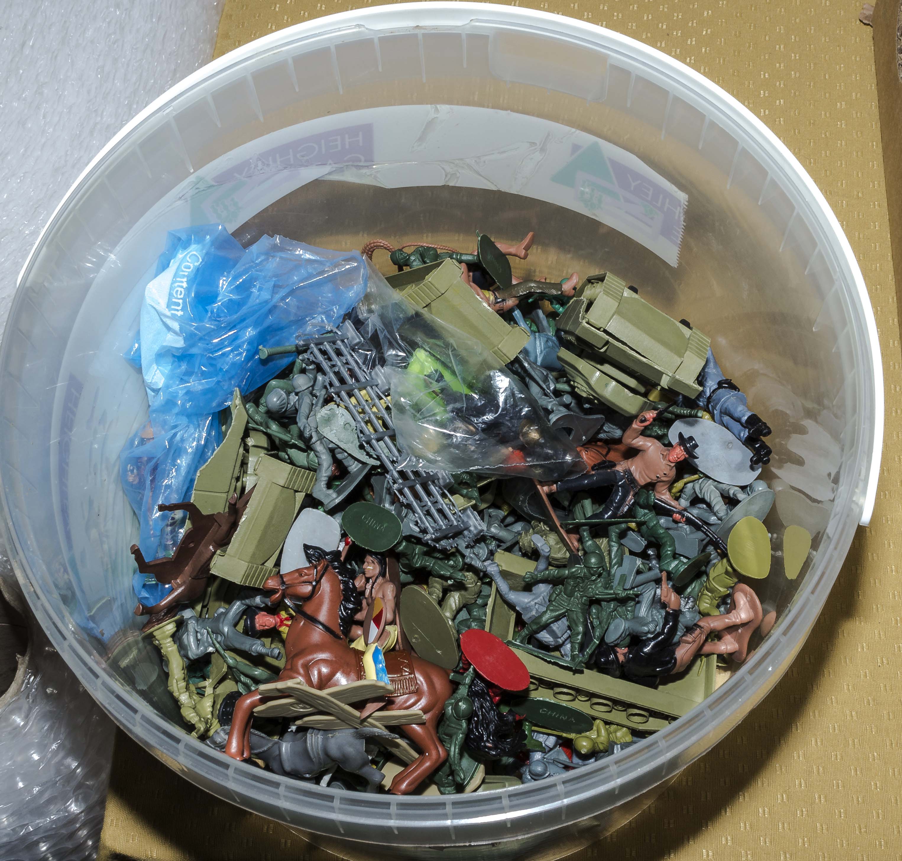 A bucket containing toy soldiers and other small toys