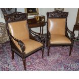 A pair of 20th century mahogany chairs with carved top rail and arms and leather upholstery. In very