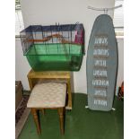 A bird cage, stool, ironing board and a small cabinet