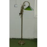 A brass standard lamp with green glass shade