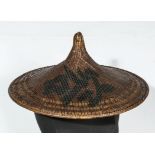 An 18th century Chinese rattan pagoda shaped hat, painted character marks to body, 56cm diameter