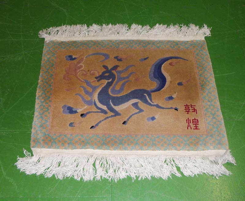 A vintage Chinese rug depicting a running horse with Chinese character marks