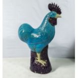 A large antique Chinese cockerel sitting on a rock, aubergine glazed base and turquoise glazed body,